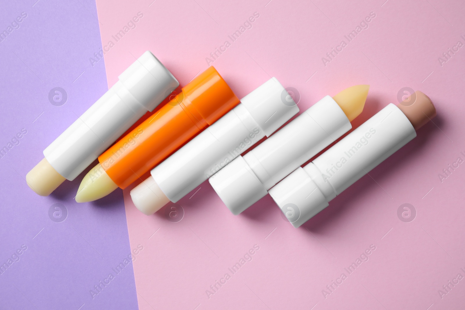 Photo of Hygienic lipsticks on color background, flat lay