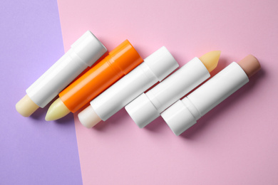 Photo of Hygienic lipsticks on color background, flat lay