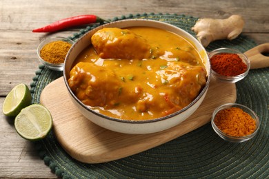 Photo of Tasty chicken curry and ingredients on wooden table