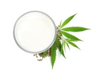Photo of Glass of fresh hemp milk, seeds and leaves on white background, top view