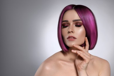 Hair styling. Attractive woman with bright purple hair on grey background, space for text