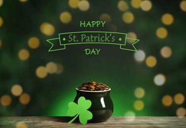 Image of Pot with gold coins and clover on wooden table. Happy St. Patrick's Day