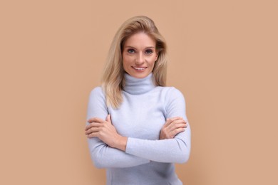 Photo of Portrait of smiling middle aged woman with crossed arms on beige background