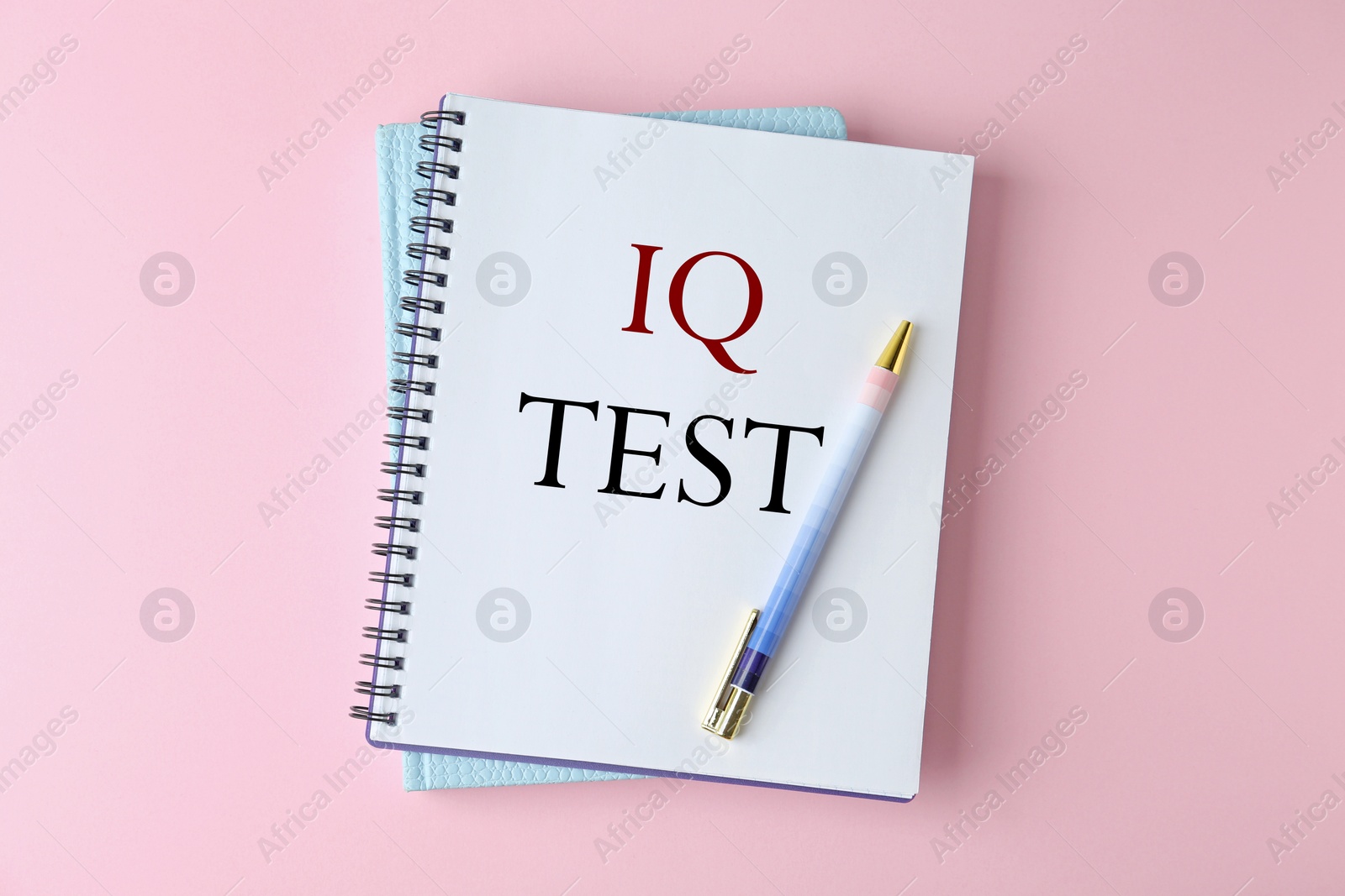 Image of Notebook with text IQ Test and pen on pink background, top view