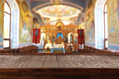 Empty wooden table and blurred view of beautiful church interior, space for text