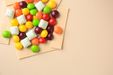 Photo of Different tasty chewing gums on beige background, flat lay. Space for text