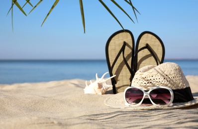 Stylish beach accessories on sand near sea