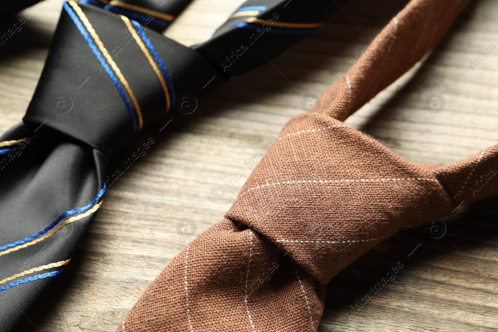 Photo of Two neckties on light wooden table, closeup