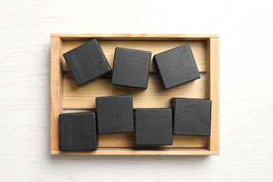 Photo of Black cubes with word KEYWORD in crate on white wooden background, top view