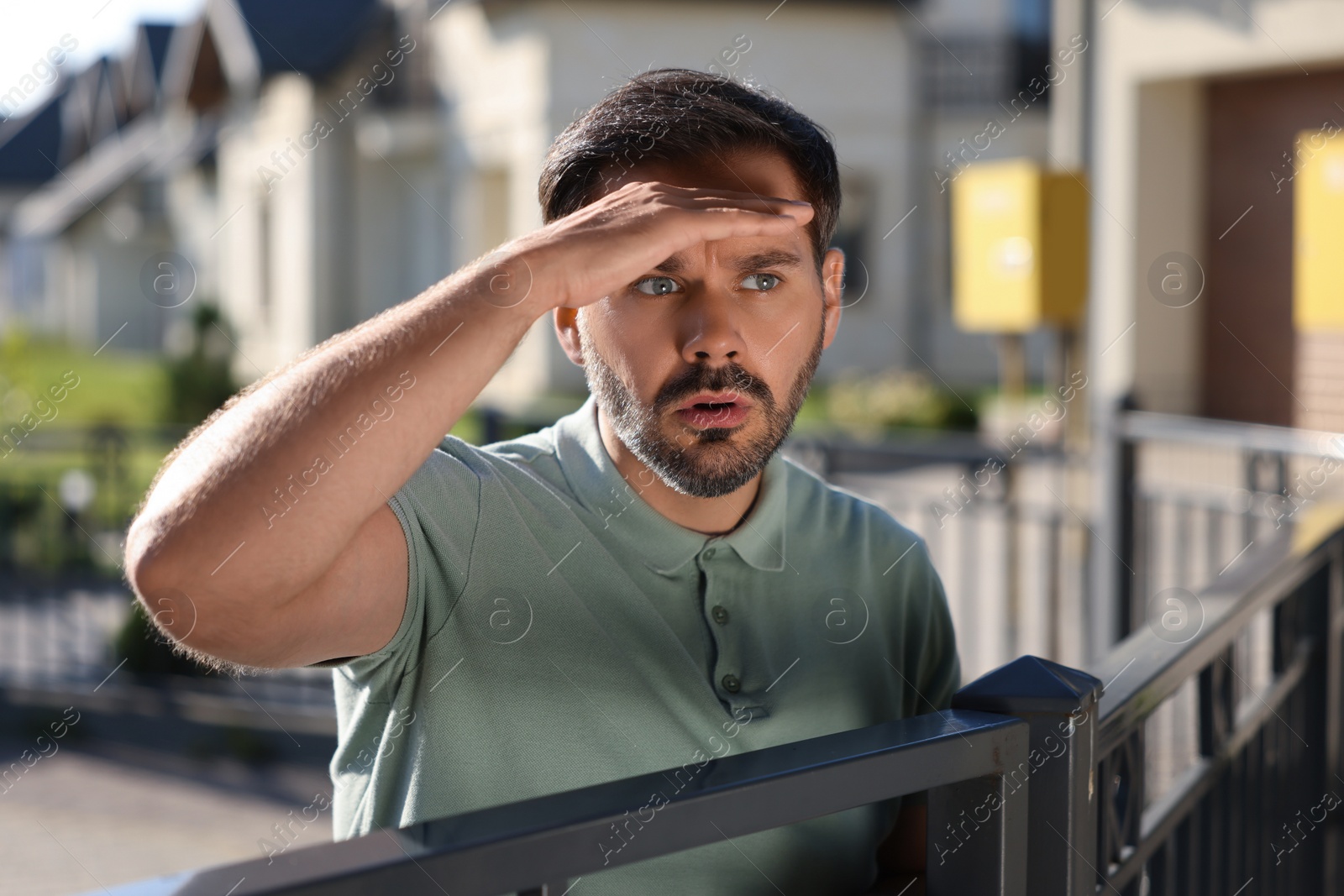 Photo of Concept of private life. Curious man spying on neighbours over fence outdoors