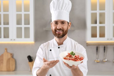 Photo of Happy chef presenting delicious dish in kitchen