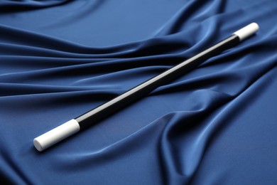 Photo of Beautiful black magic wand on blue fabric