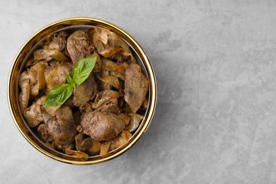 Delicious fried chicken liver with onion in bowl on light grey table, top view. Space for text