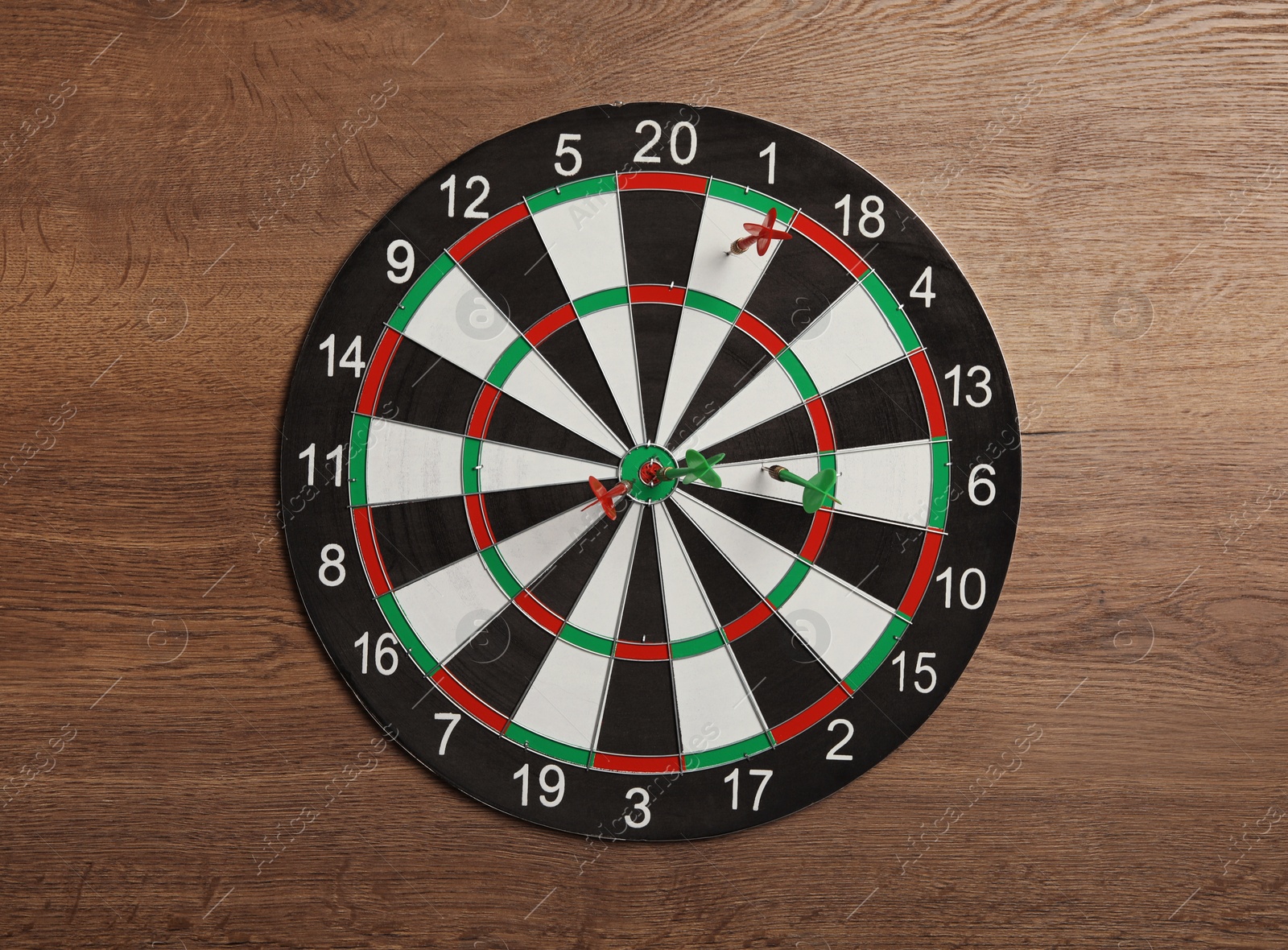 Photo of Dart board with color arrows on wooden background, top view