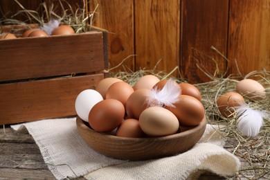 Photo of Fresh chicken eggs and dried hay on wooden table