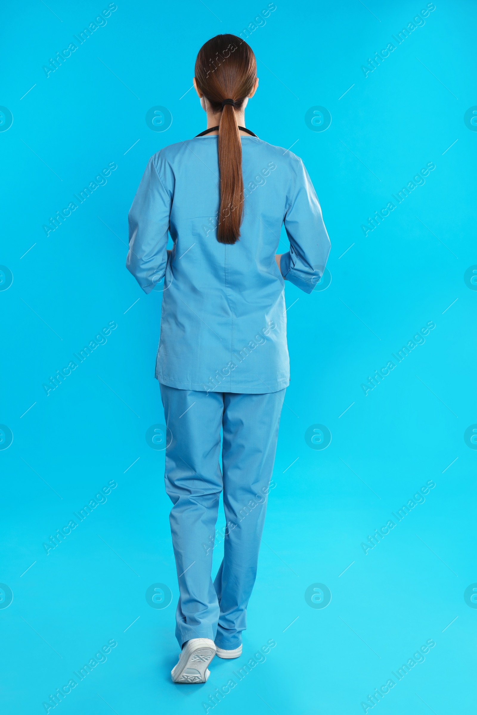 Photo of Doctor in uniform walking on blue background
