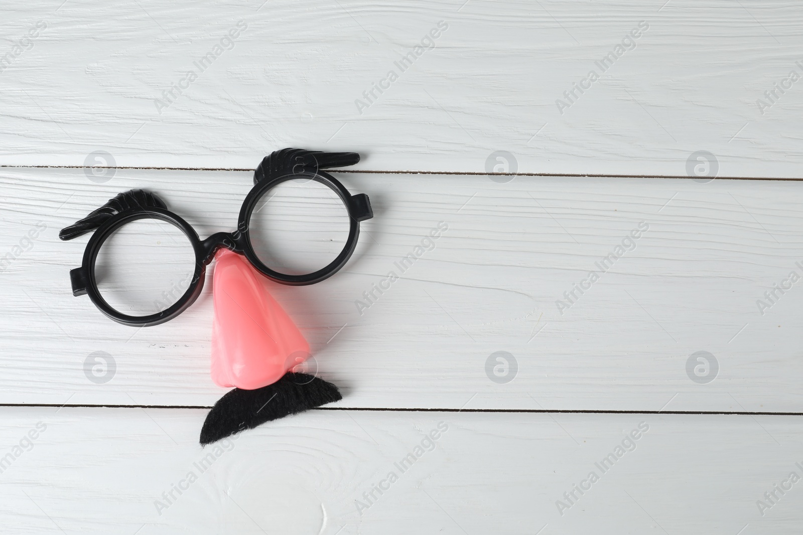 Photo of Funny mask with fake mustache, nose and glasses on white wooden background, top view. Space for text