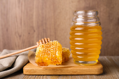 Photo of Jar of tasty aromatic honey and combs on wooden table