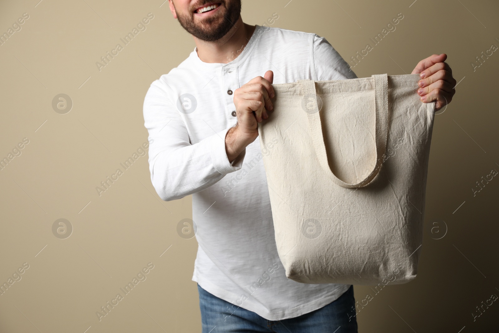 Photo of Happy man with eco bag on beige background, closeup. Space for text