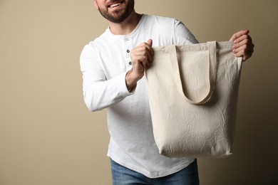Happy man with eco bag on beige background, closeup. Space for text