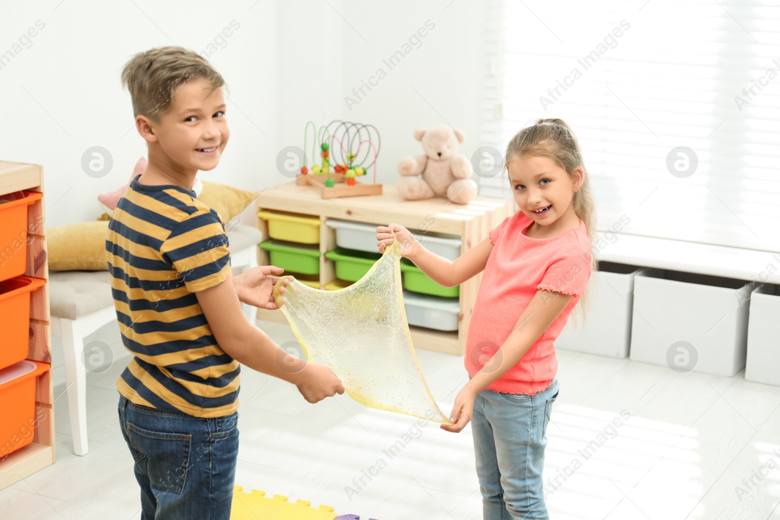 Photo of Happy children playing with slime in room