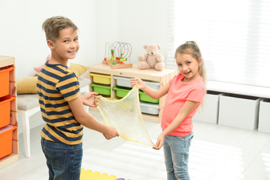 Happy children playing with slime in room