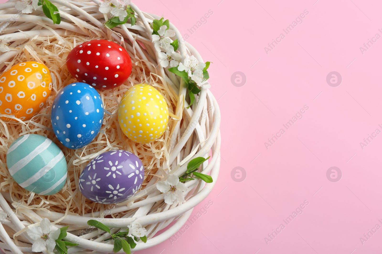 Photo of Nest with painted Easter eggs and space for text on color background, top view