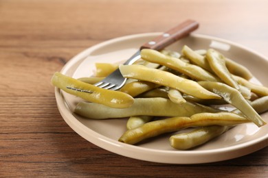Photo of Canned green beans on wooden table, closeup