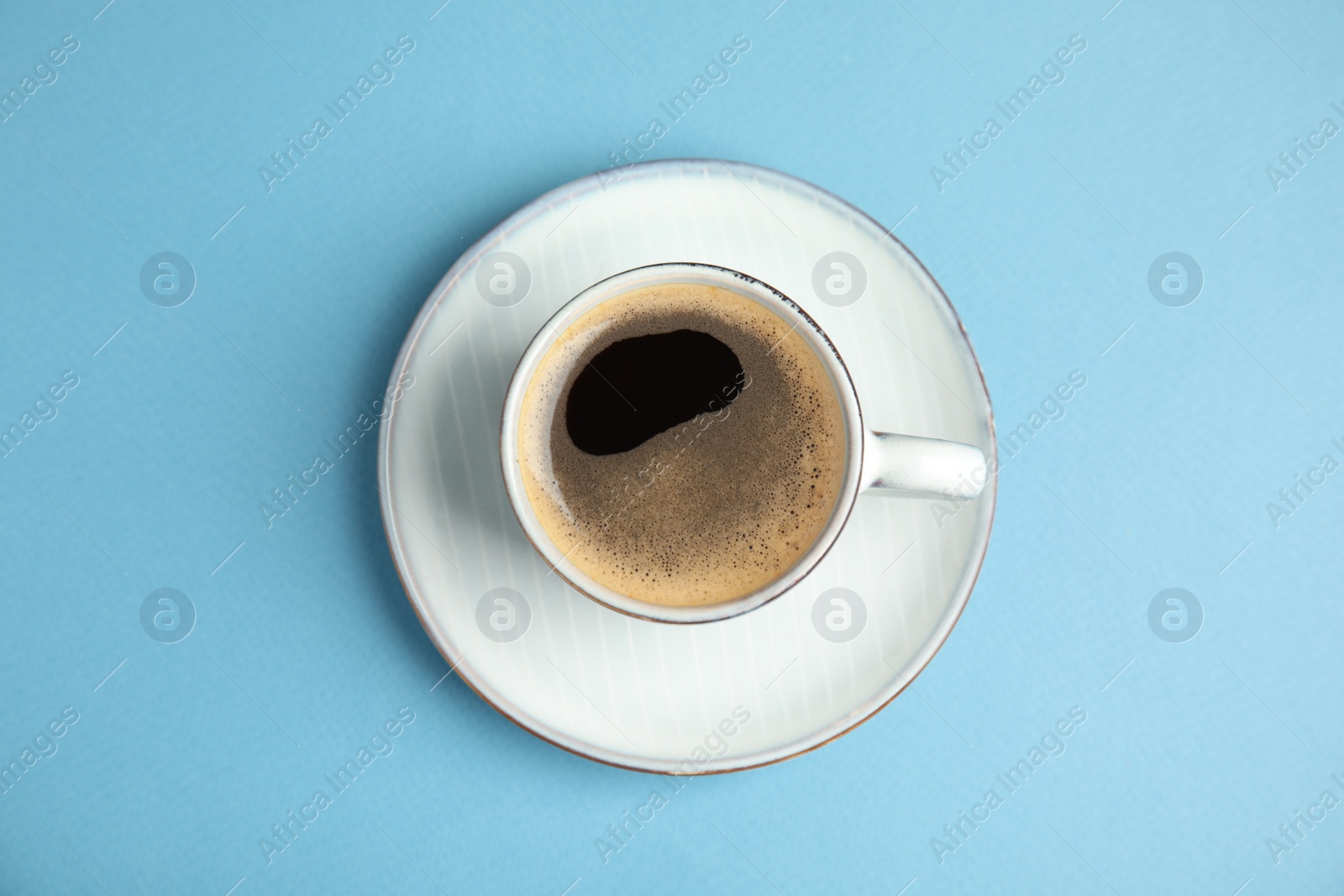 Photo of Cup of hot aromatic espresso on light blue background, top view