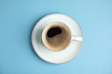 Photo of Cup of hot aromatic espresso on light blue background, top view