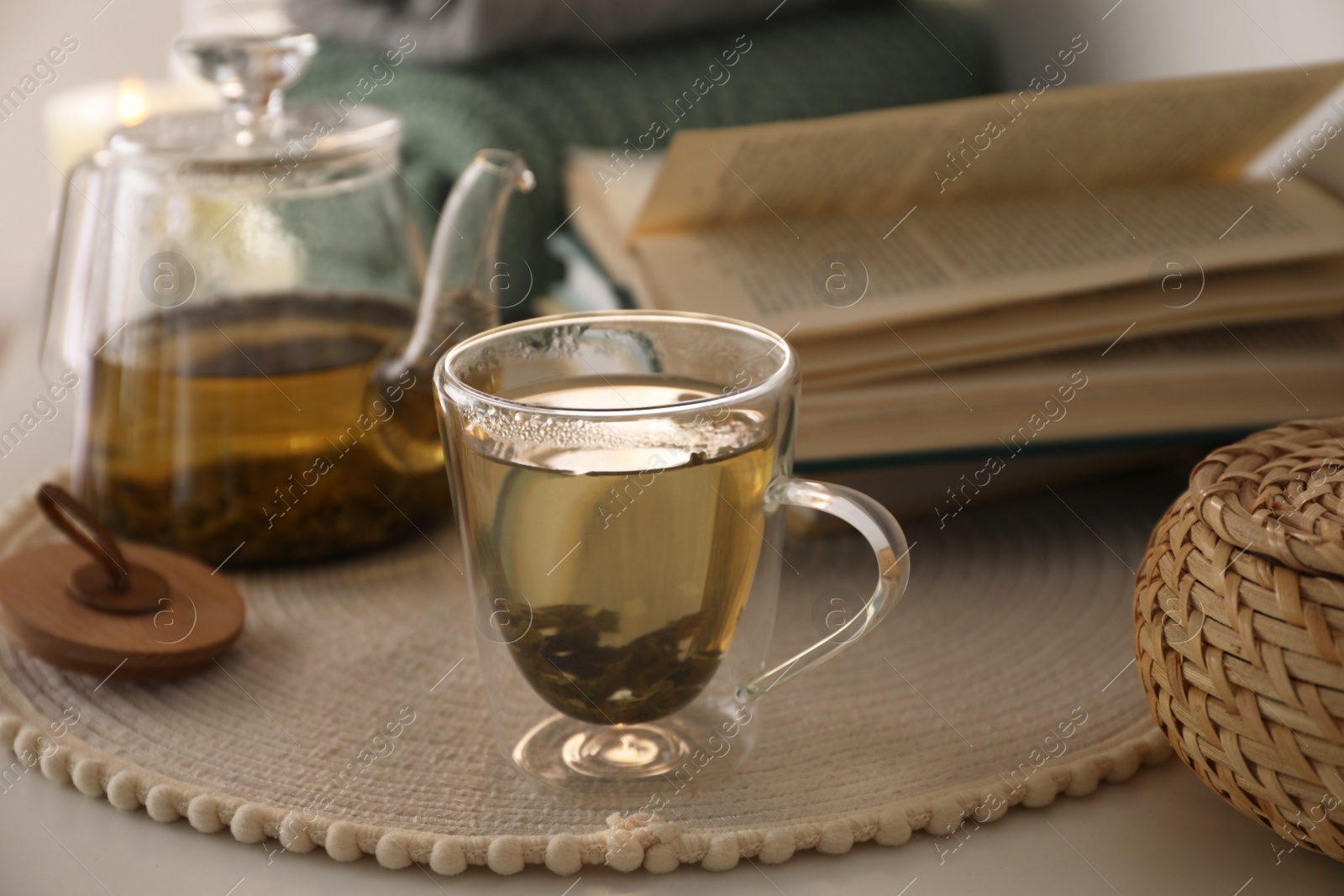 Photo of Glass teapot and cup of hot tea on table in room. Cozy home atmosphere