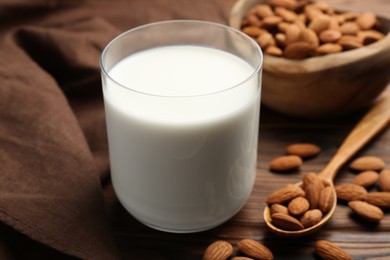 Glass of almond milk and almonds on wooden table