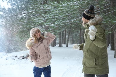 Happy couple playing snowballs in winter forest