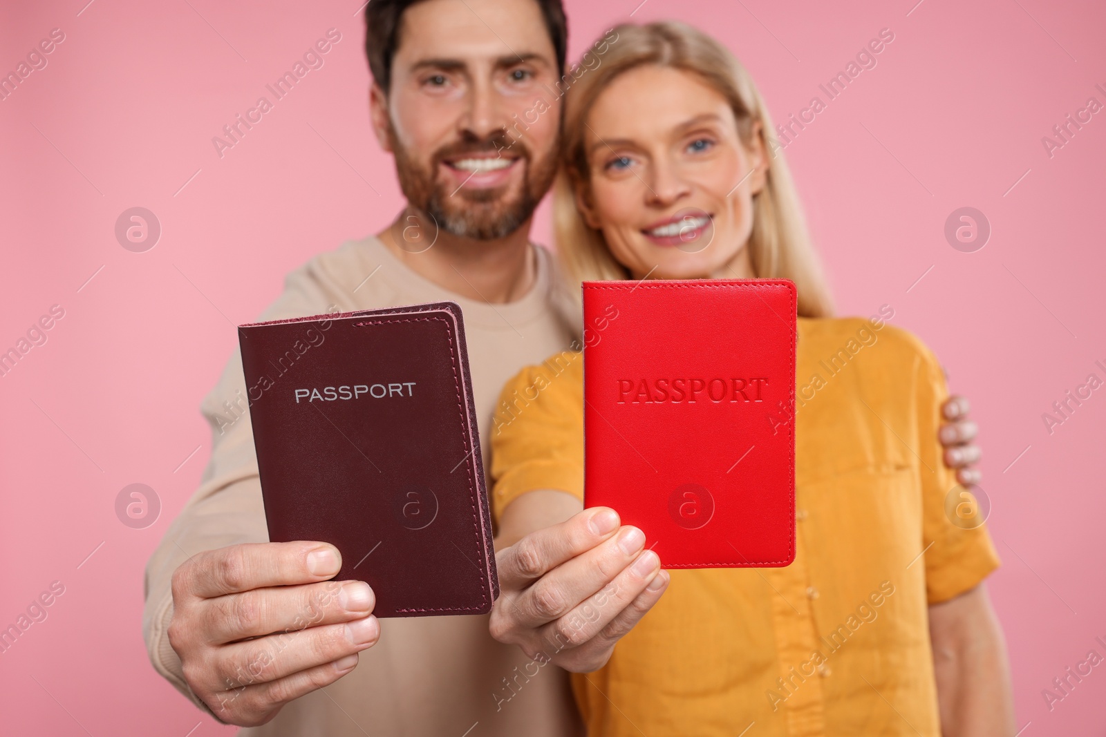 Photo of Immigration. Happy couple with passports on pink background, selective focus