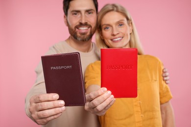 Immigration. Happy couple with passports on pink background, selective focus