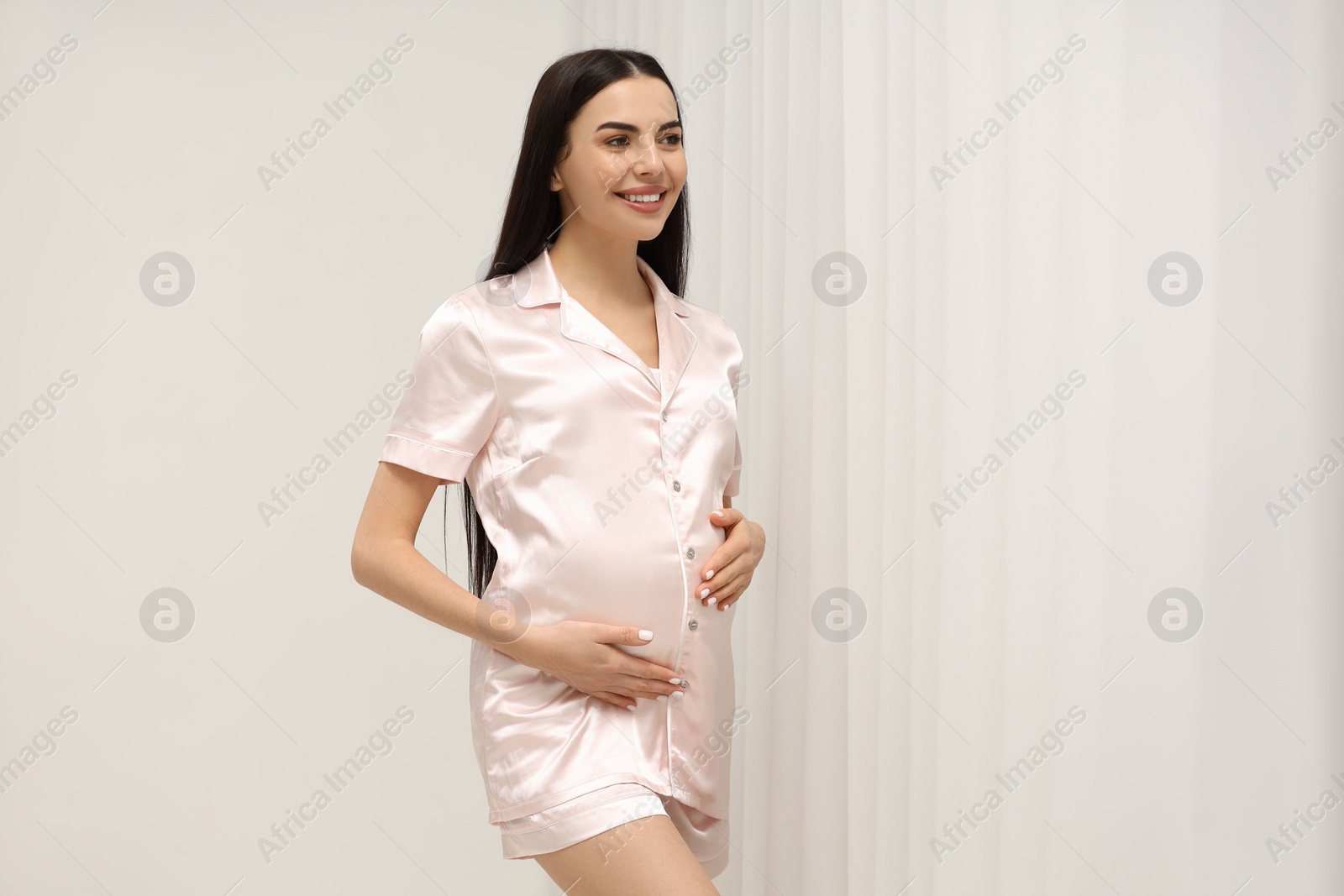 Photo of Happy pregnant woman near window indoors, space for text