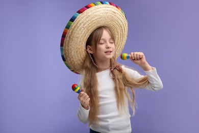 Cute girl in Mexican sombrero hat singing with maracas on purple background