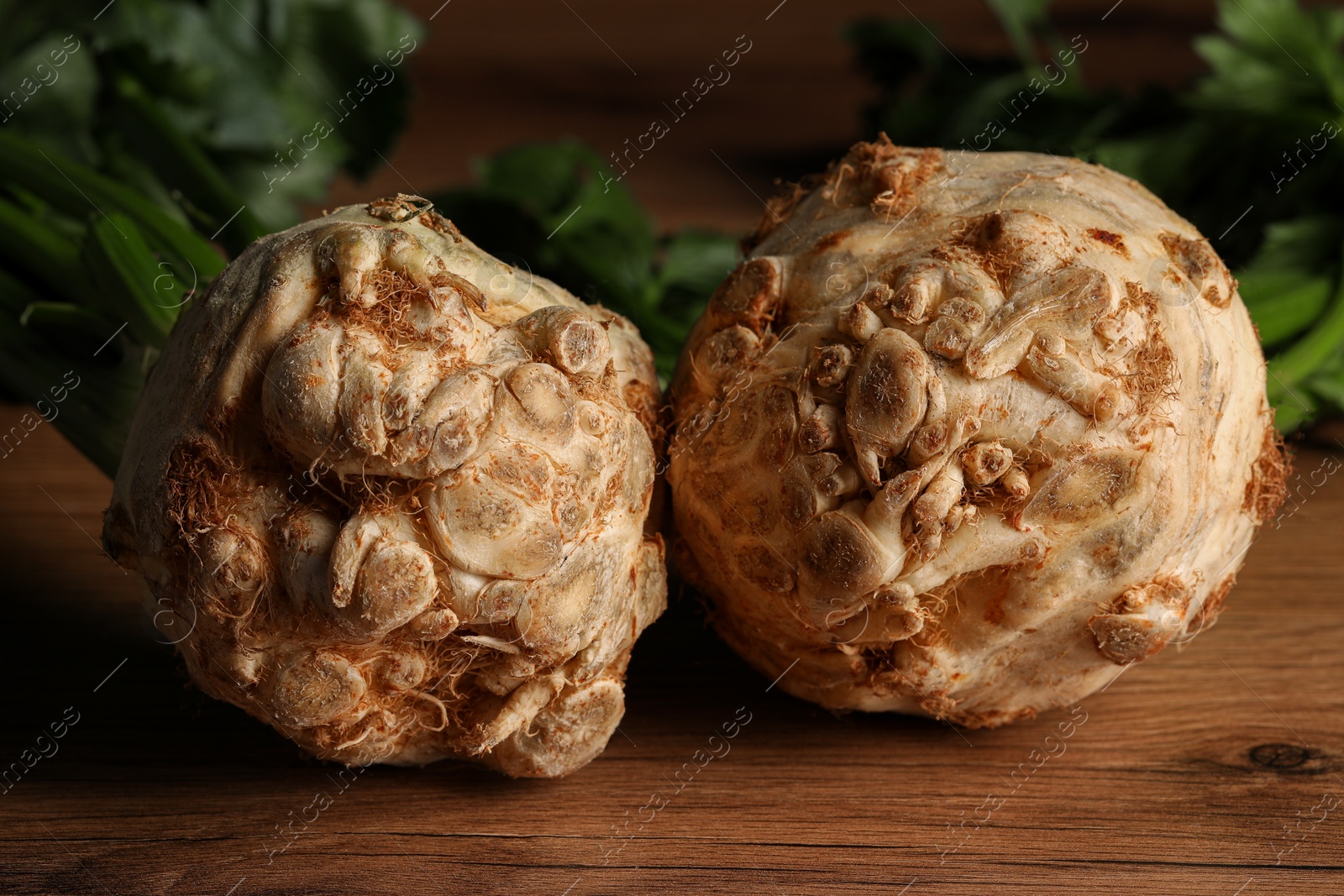 Photo of Fresh raw celery roots on wooden table, closeup