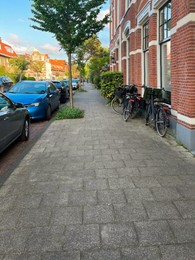 Beautiful view of city street with modern houses, bicycles and parked cars