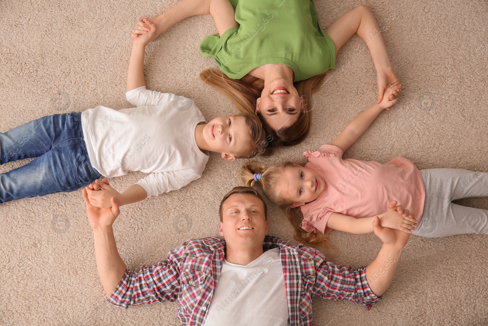 Photo of Happy family lying on cozy carpet at home, top view
