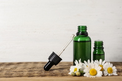 Photo of Composition with bottles of chamomile essential oil on table. Space for text