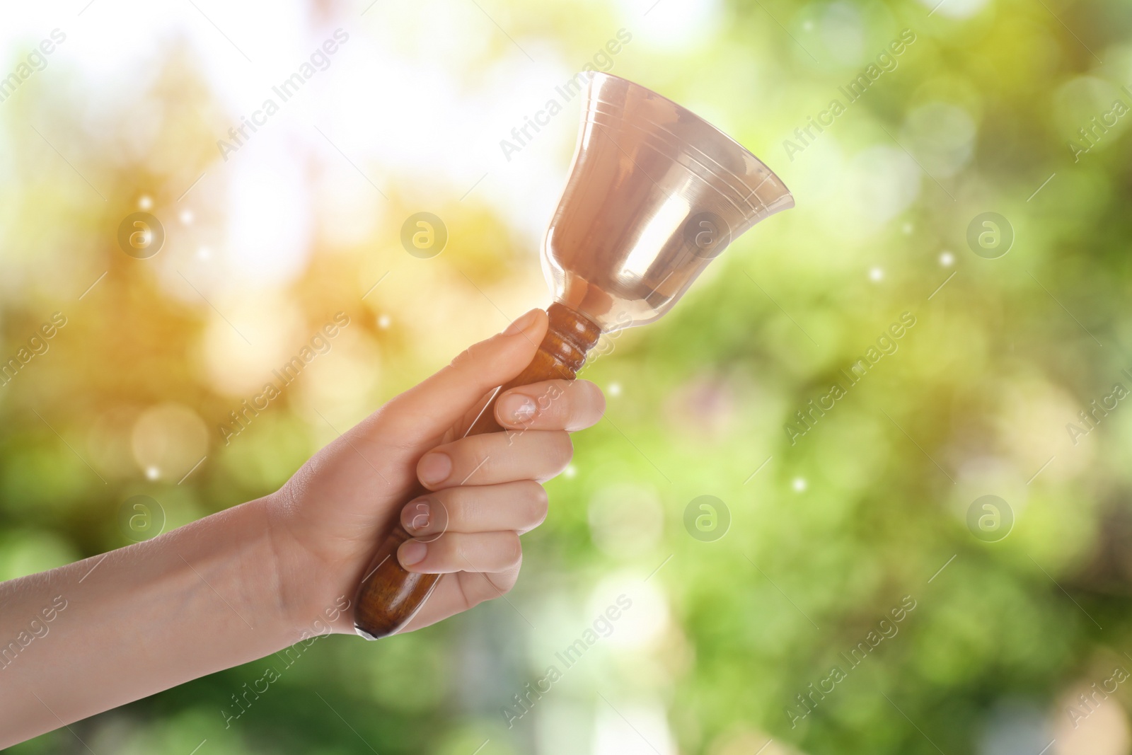 Image of Woman with school bell outdoors, closeup. Bokeh effect