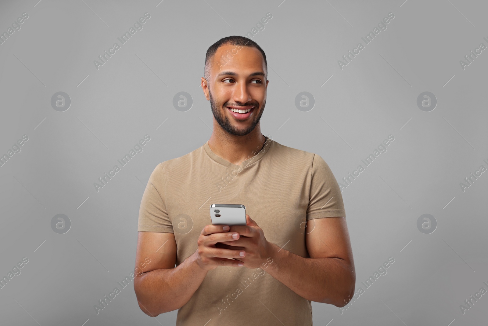 Photo of Happy man sending message via smartphone on grey background