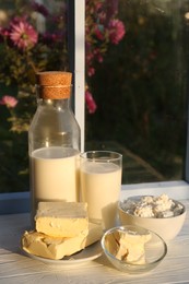 Photo of Tasty homemade butter and dairy products on white wooden windowsill