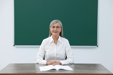 Photo of Portrait of professor sitting at desk in classroom