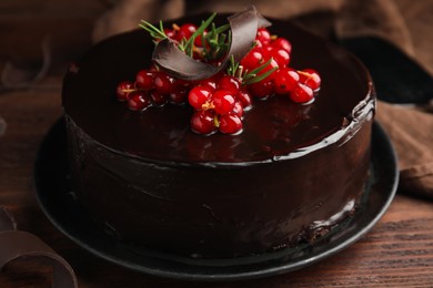 Photo of Tasty homemade chocolate cake with berries and rosemary on wooden table, closeup