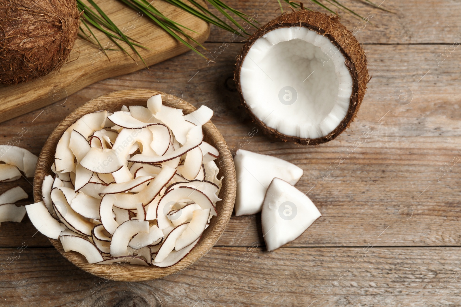 Photo of Flat lay composition with tasty coconut chips on wooden table