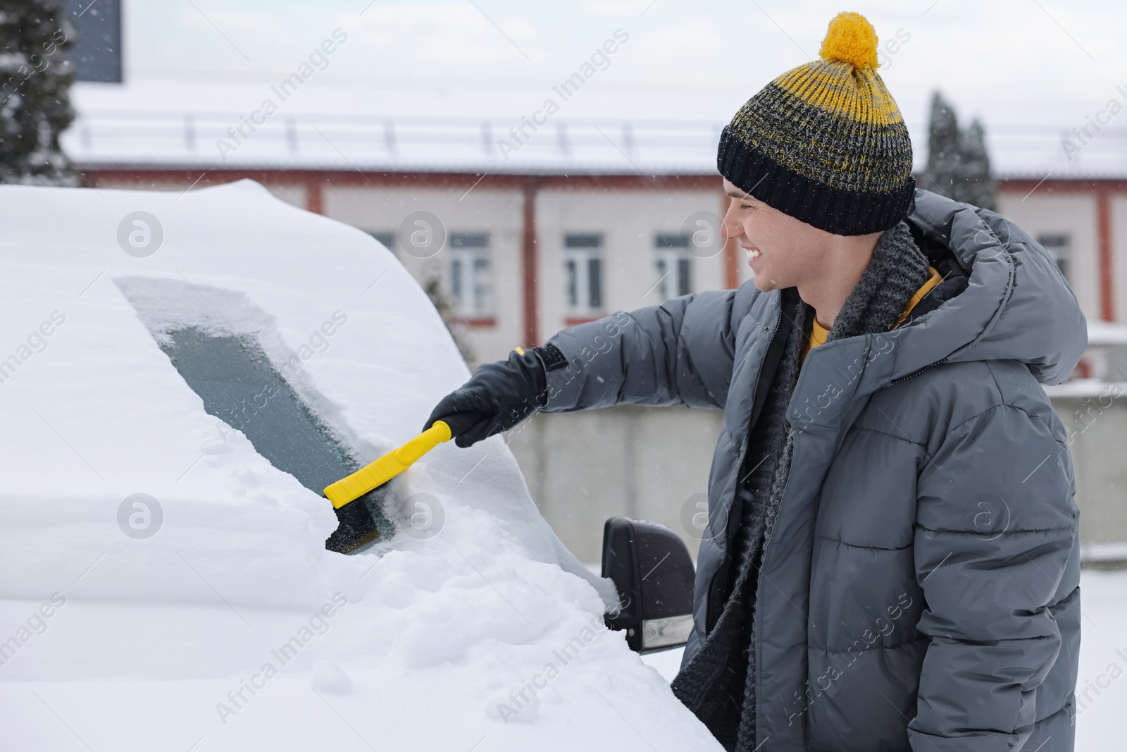 Photo of Man cleaning snow from car windshield outdoors