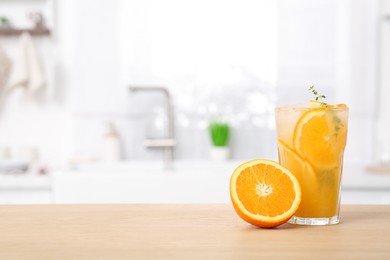 Glass of tasty orange juice and fruit on wooden counter in kitchen, space for text