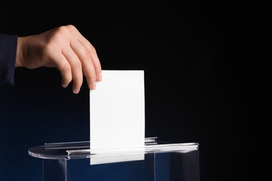 Photo of Woman putting her vote into ballot box on dark blue background, closeup. Space for text